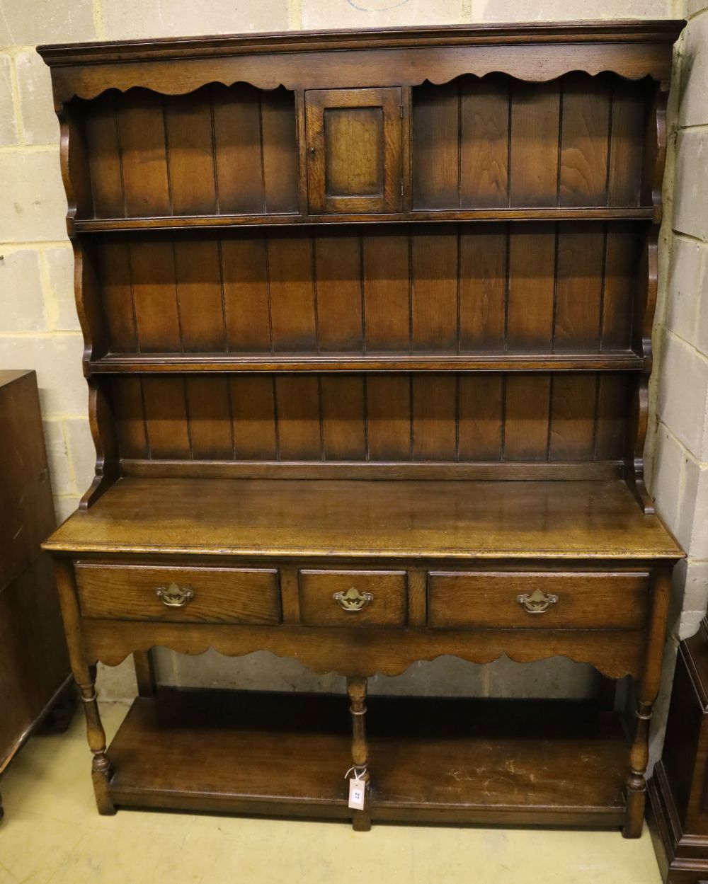 A small Georgian style reproduction oak dresser, having shelved boarded back, shaped apron and pot shelf, width 137cm, depth 44cm, heig